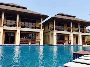 Ein Hotel mit Schwimmbad, mehreren Balkonen und einer gefliesten Poolkante.