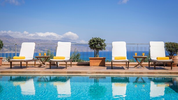 A poolside area with lounge chairs and a view of the ocean. - Caneva Luxury Villa (Platanias)