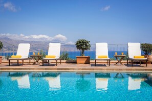 A poolside area with lounge chairs and a view of the ocean.