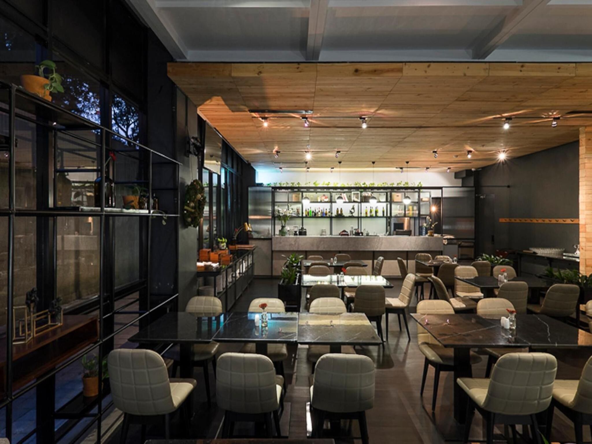 A modern restaurant with a bar area, multiple tables, and chairs.