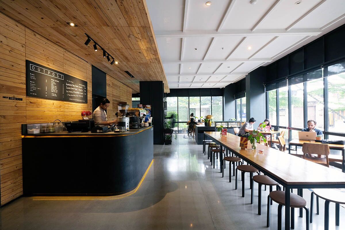 Um café moderno com balcão de madeira, quadro de menu e grandes janelas.
