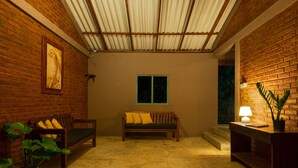 A cozy room with a wooden bench, a small table with a lamp, and a potted plant. - Hide Yala (Thissamaharama)