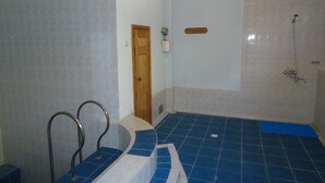 A bathroom with a blue-tiled floor, a shower, and a wooden door.