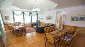 A spacious living room with wooden furniture, a television, and artwork on the walls.