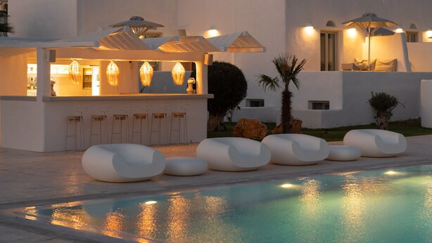 Un edificio moderno con piscina, zona de estar al aire libre y bar.
