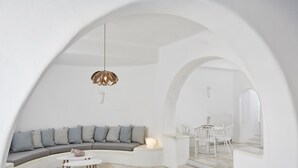 Un interior moderno con un sofá curvo, una mesa de centro redonda y un comedor con sillas blancas.