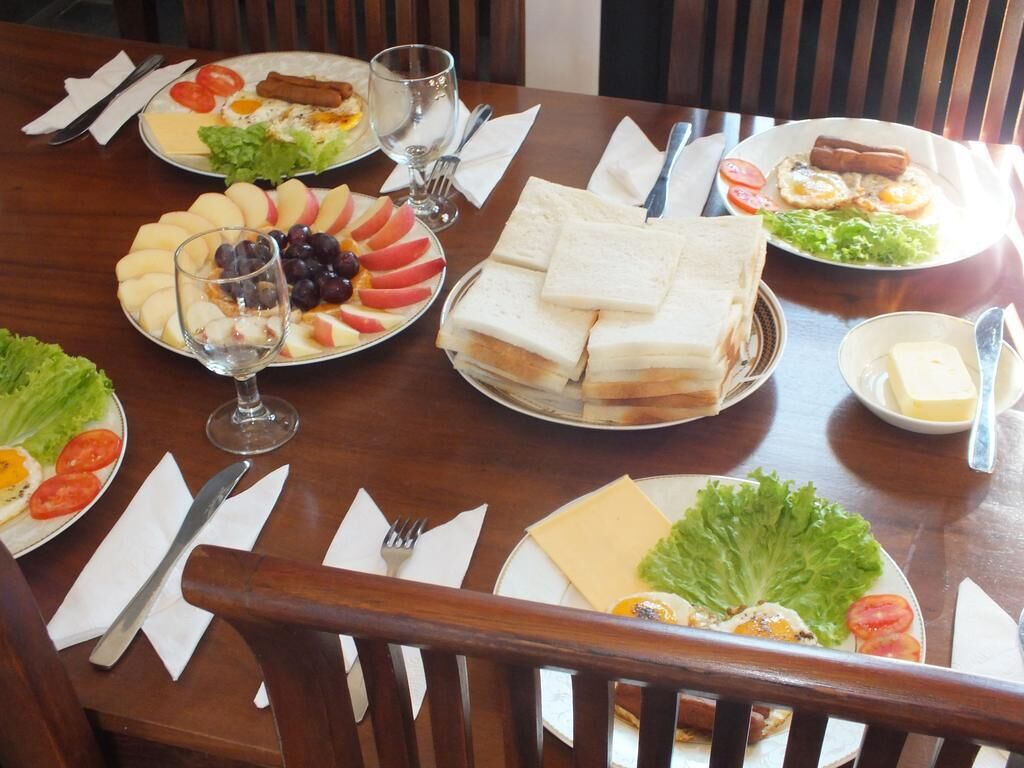 A dining table with various plates of food, including sandwiches, salads, and a glass of wine.