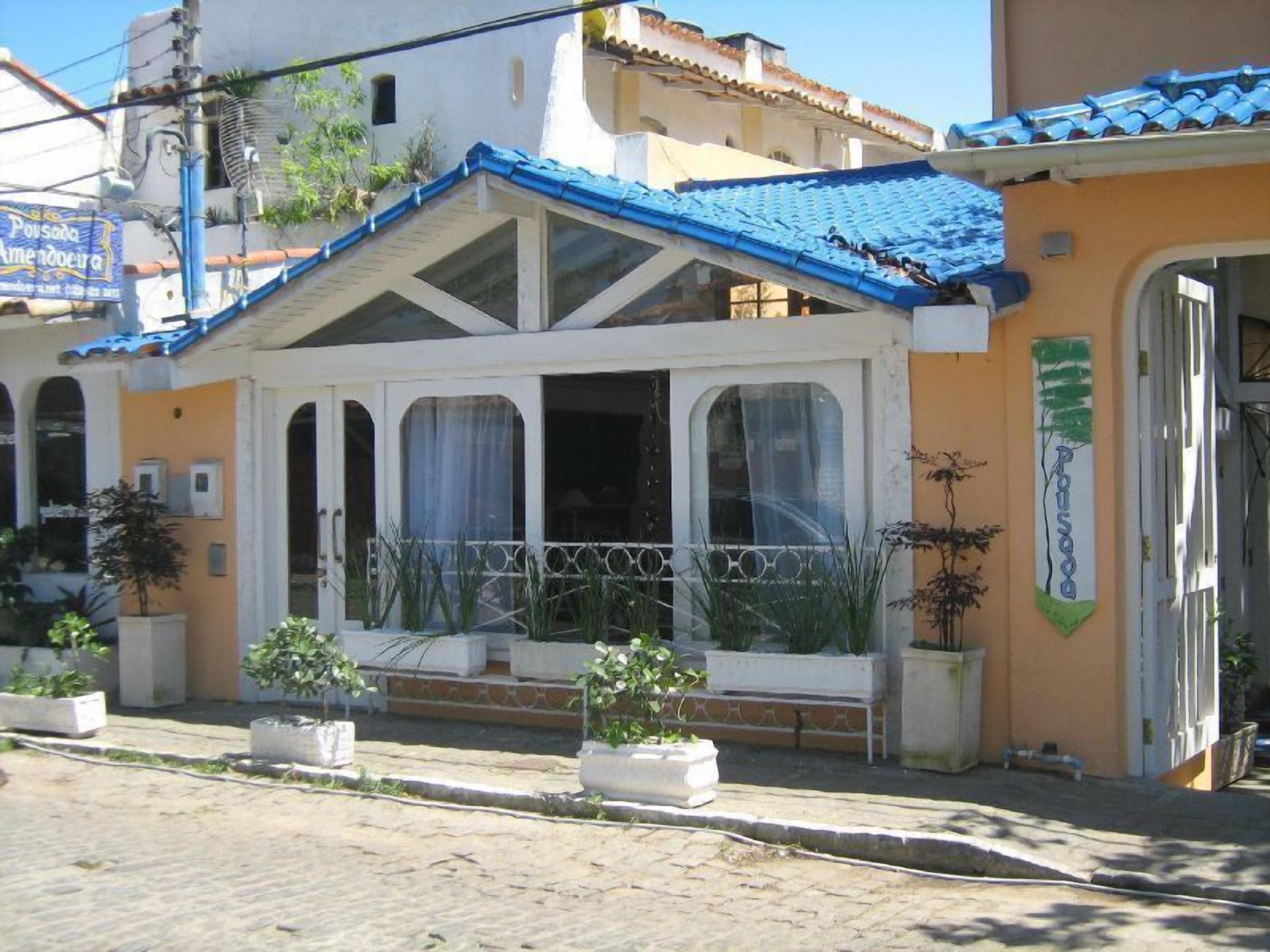A building with a blue tiled roof, white walls, and a balcony with potted plants.