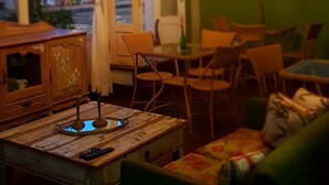 A cozy living room with a chandelier, a television, and a view of the street outside. - Pousada Amendoeira (Búzios)