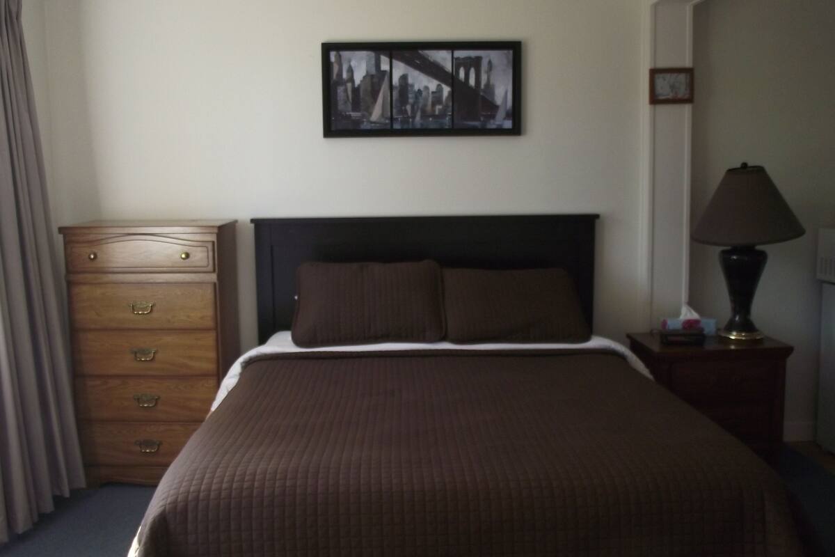 Ein Hotelzimmer mit einem Bett, einem Schminktisch, einer Lampe und einem gerahmten Bild an der Wand.