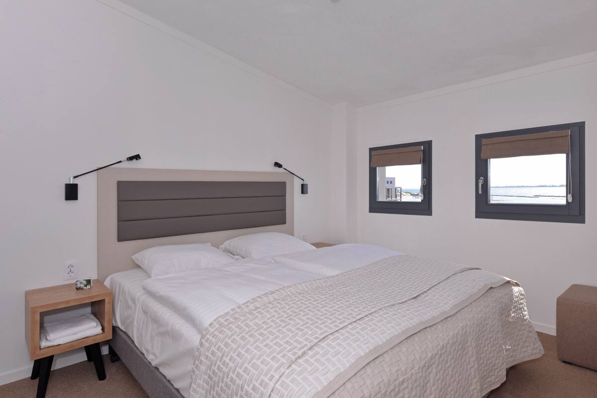 Una camera da letto con un letto, comodini e due finestre con persiane.