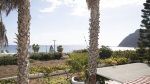 Vista de una zona costera con palmeras, un jardín y un edificio de techo rojo.