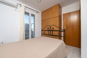 A bedroom with a bed, wooden wardrobe, and a sliding glass door.