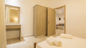 Un dormitorio con cama, armario de madera, baño con espejo y escritorio.