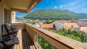 Ein Balkon mit Holzboden und Blick auf eine Stadt und ein Gebirge.