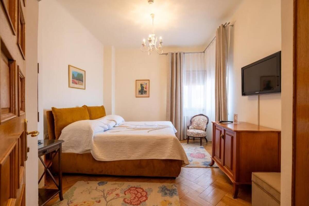 Un dormitorio con una cama, un aparador de madera, un televisor y una silla.
