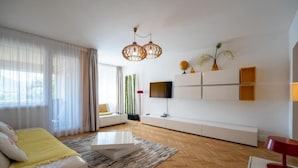 Ein modernes Wohnzimmer mit einer Couch, einem Couchtisch und einem an einer weißen Wand befestigten Fernseher.