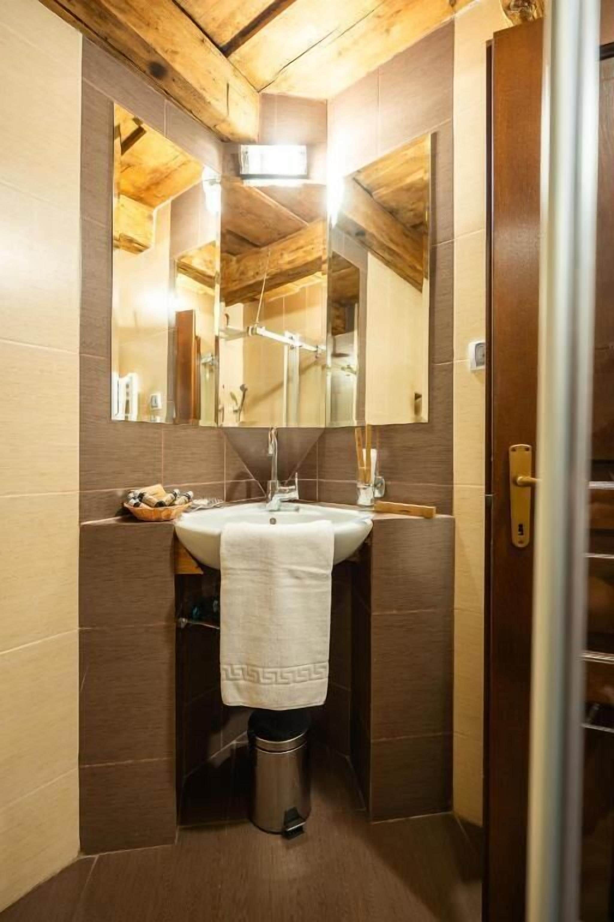 Une salle de bain avec un plafond en bois, un grand miroir, un lavabo et une serviette accrochée au mur.
