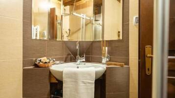 Une salle de bain avec un plafond en bois, un grand miroir, un lavabo et une serviette accrochée au mur.