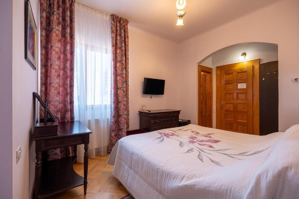 A bedroom with a bed, a desk, a television, and a wardrobe.