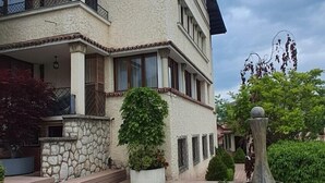Ein mehrgeschossiges Gebäude mit einer steinernen Fassade, Balkonen und einem gepflasterten Weg.