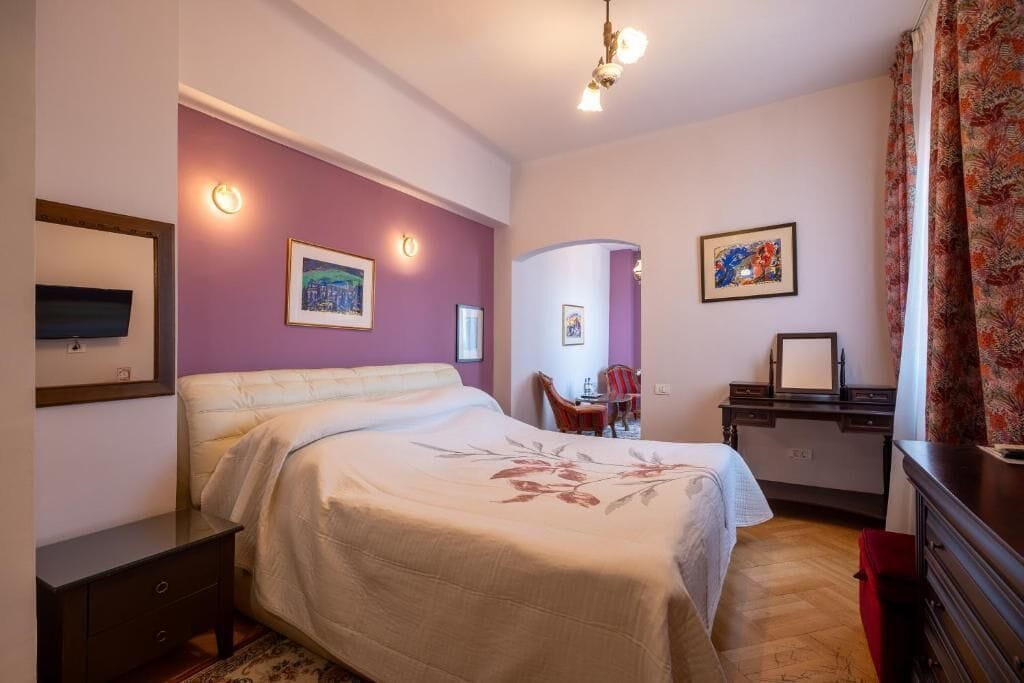 Een slaapkamer met een bed, nachtkastjes, een bureau en stoelen.