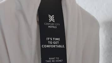 Une blouse blanche est suspendue à un portant, avec une étiquette indiquant « Hôtels de Century City » et « Il est temps de se détendre. »