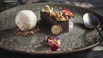 Un plato de postre con un brownie, helado y adornos.
