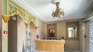A hotel lobby with a marble floor, a reception desk, a chandelier, and a large mirror. - Hotel Saheb Ettabaa (Tunis)