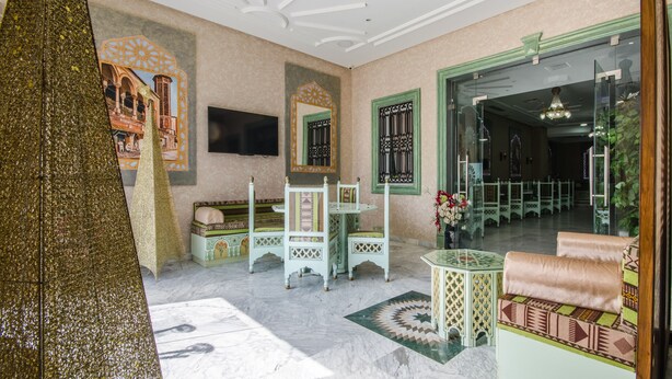 A room with a bed, a small table, a chair, a TV, and a decorative mirror. - Hotel Saheb Ettabaa (Tunis)