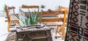 Un cofre de madera con intrincados grabados, colocado sobre una mesa en una habitación con sillas de madera y plantas verdes.