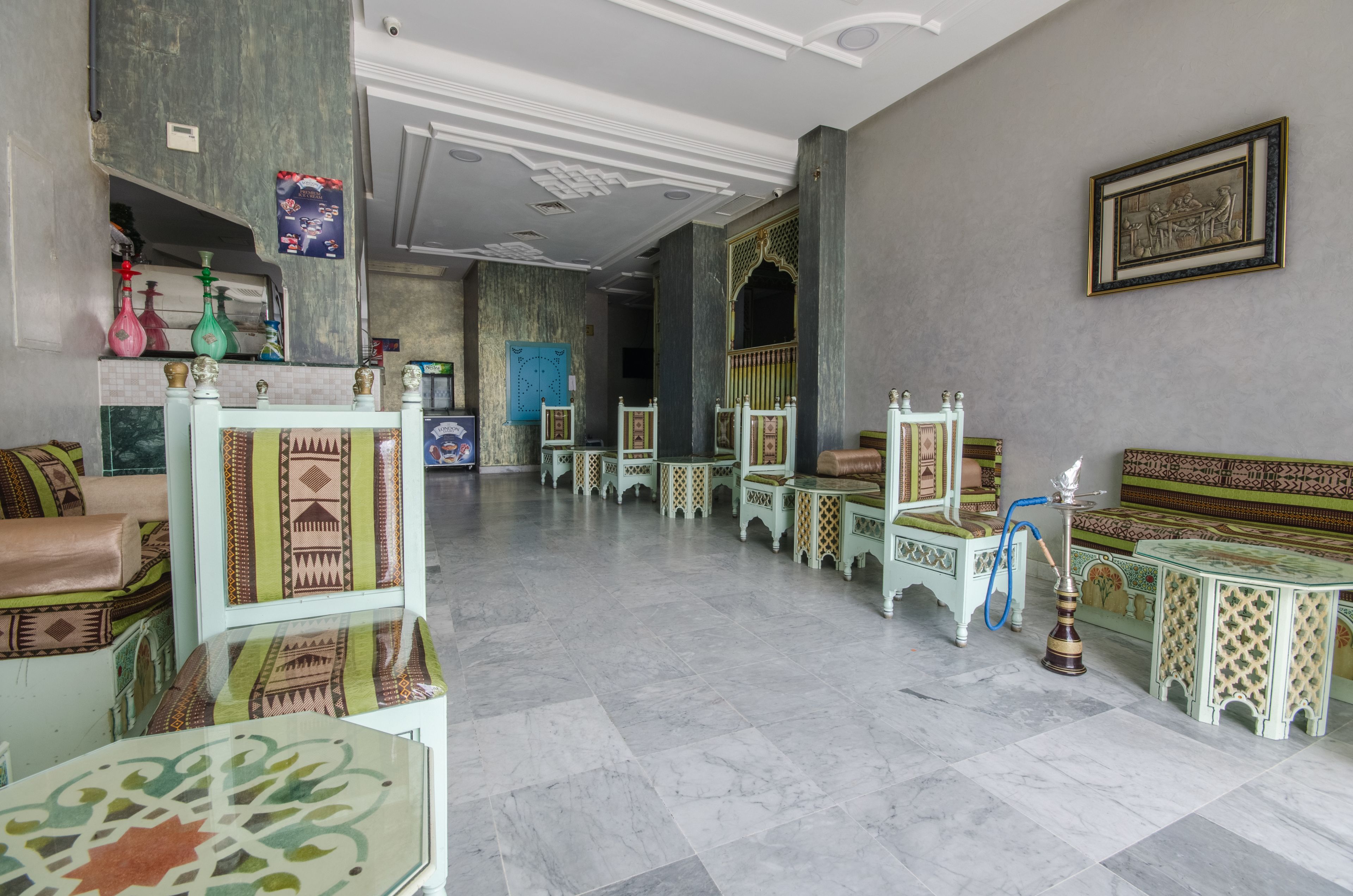 Un hall d’entrée spacieux avec un sol en marbre, des meubles aux motifs traditionnels et un présentoir pour narguilé.