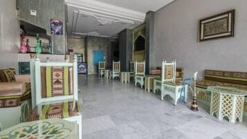 Un hall d’entrée spacieux avec un sol en marbre, des meubles aux motifs traditionnels et un présentoir pour narguilé.