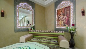 A room with a patterned bench, a mirror with decorative framing, and a wall-mounted painting. - Hotel Saheb Ettabaa (Tunis)