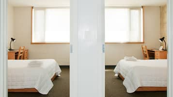 Une vue en miroir d’une chambre d’hôtel avec deux lits, un bureau et une fenêtre.