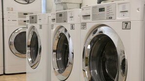 Hilera de lavadoras comerciales blancas, numeradas 5, 6 y 7, en un establecimiento.