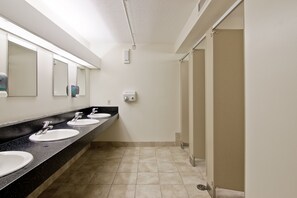 A public restroom with three sinks, a hand dryer, and a paper towel dispenser.