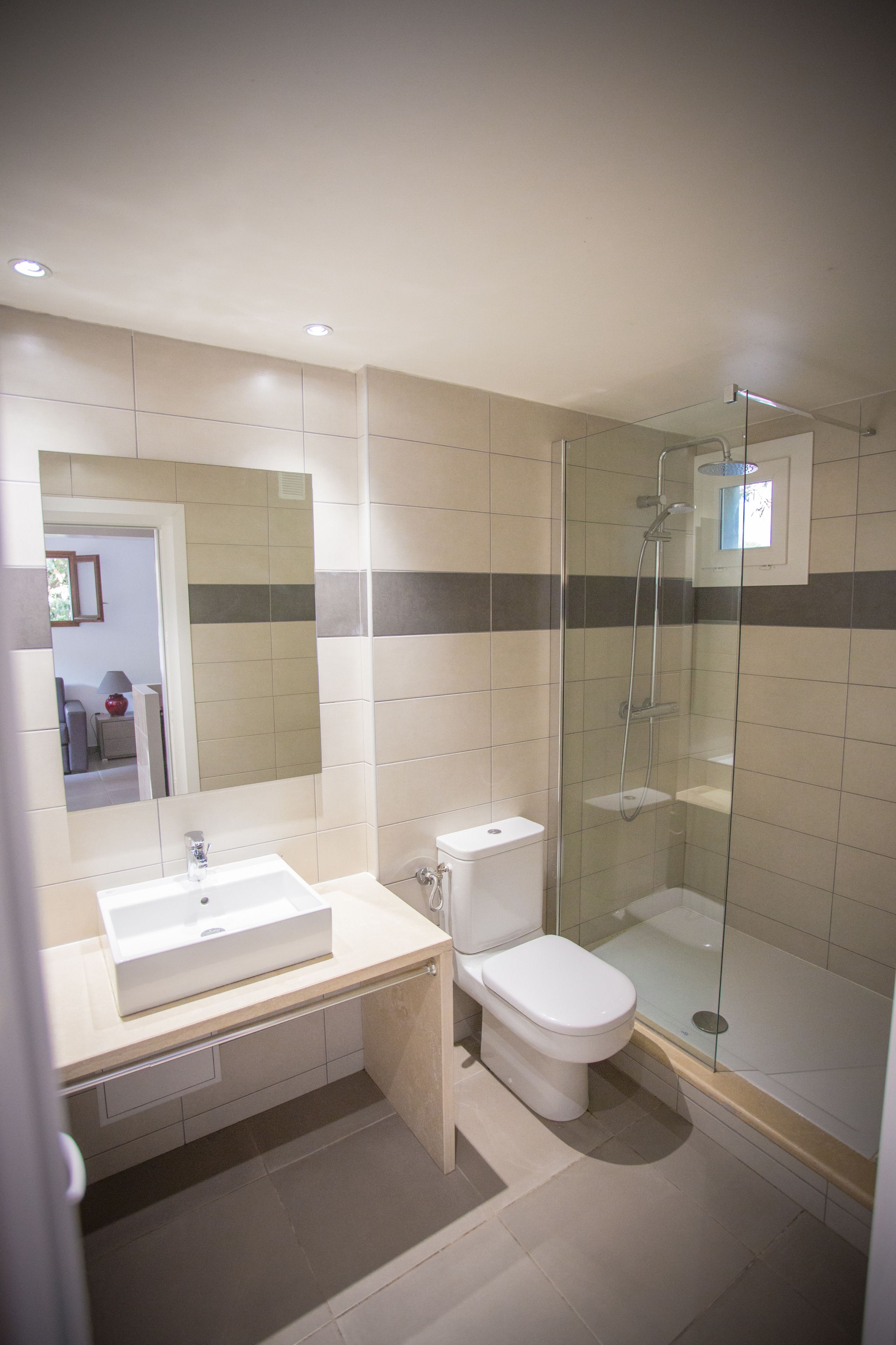 Une salle de bain moderne avec une douche à parois de verre, un lavabo blanc et des toilettes.