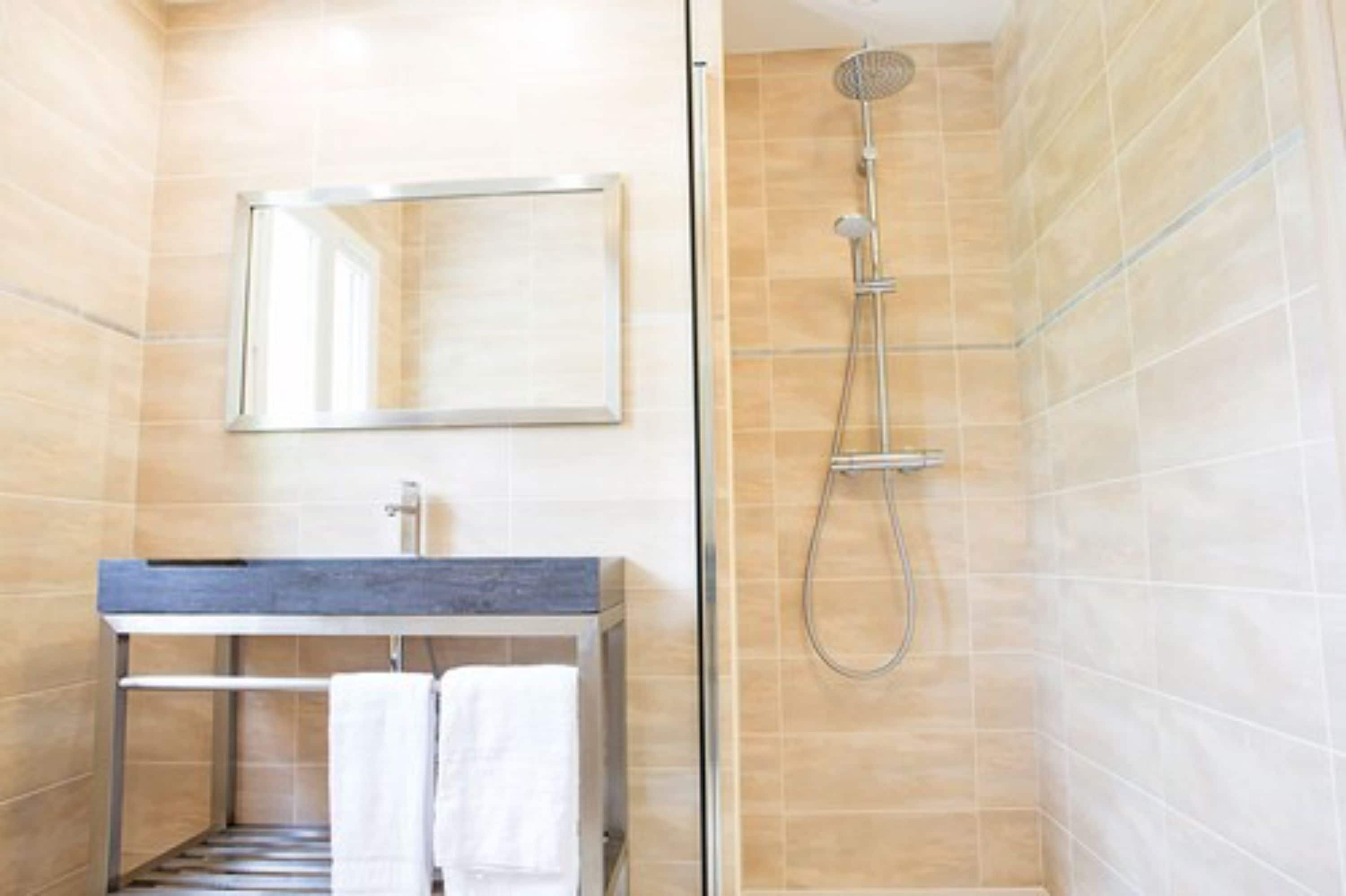 Une salle de bain moderne avec une douche, un lavabo et un miroir.