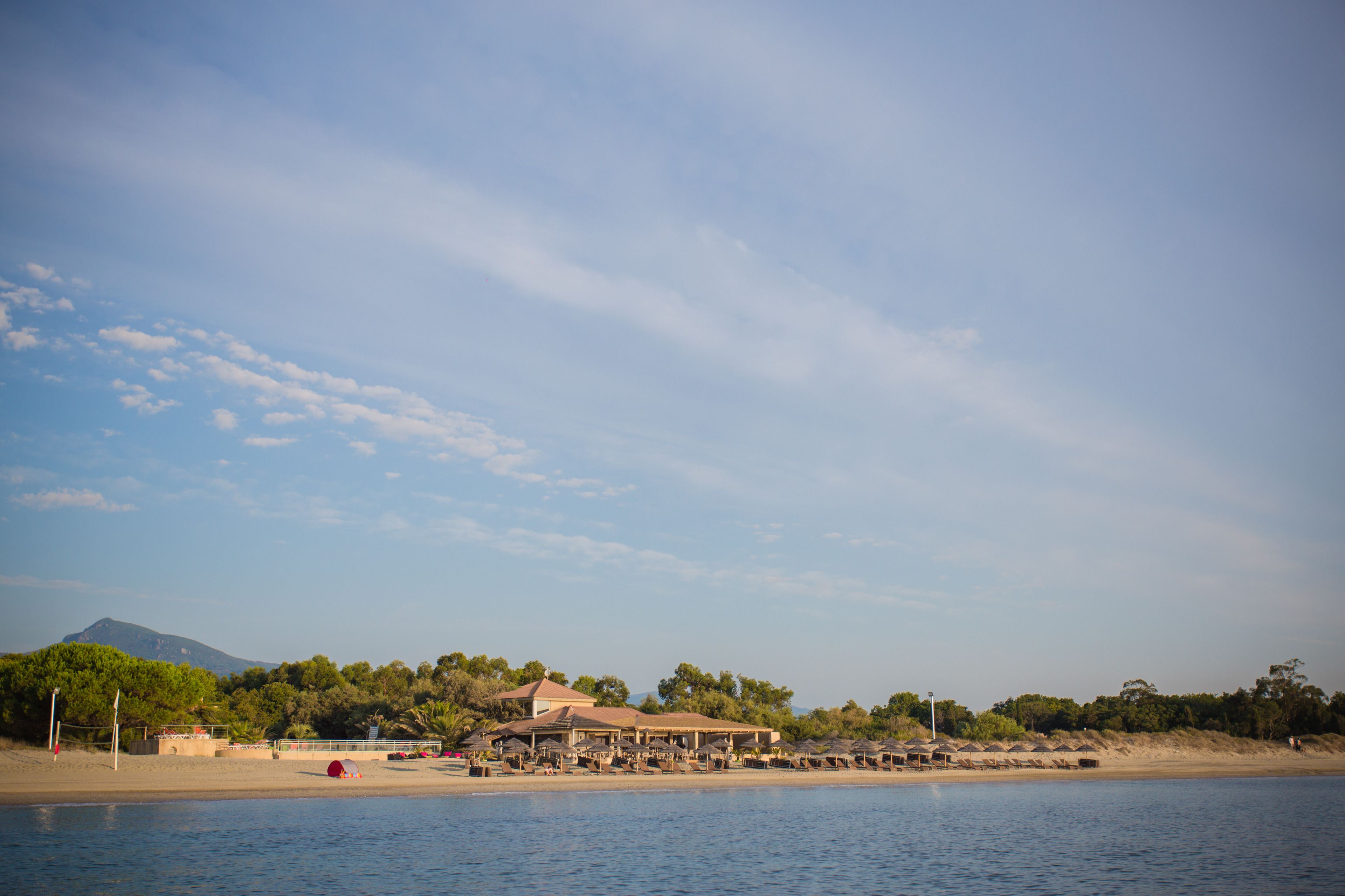 A beachfront hotel with multiple structures, including a main building and several smaller ones, likely offering beachside amenities.