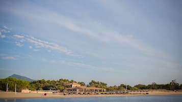 A beachfront hotel with multiple structures, including a main building and several smaller ones, likely offering beachside amenities.