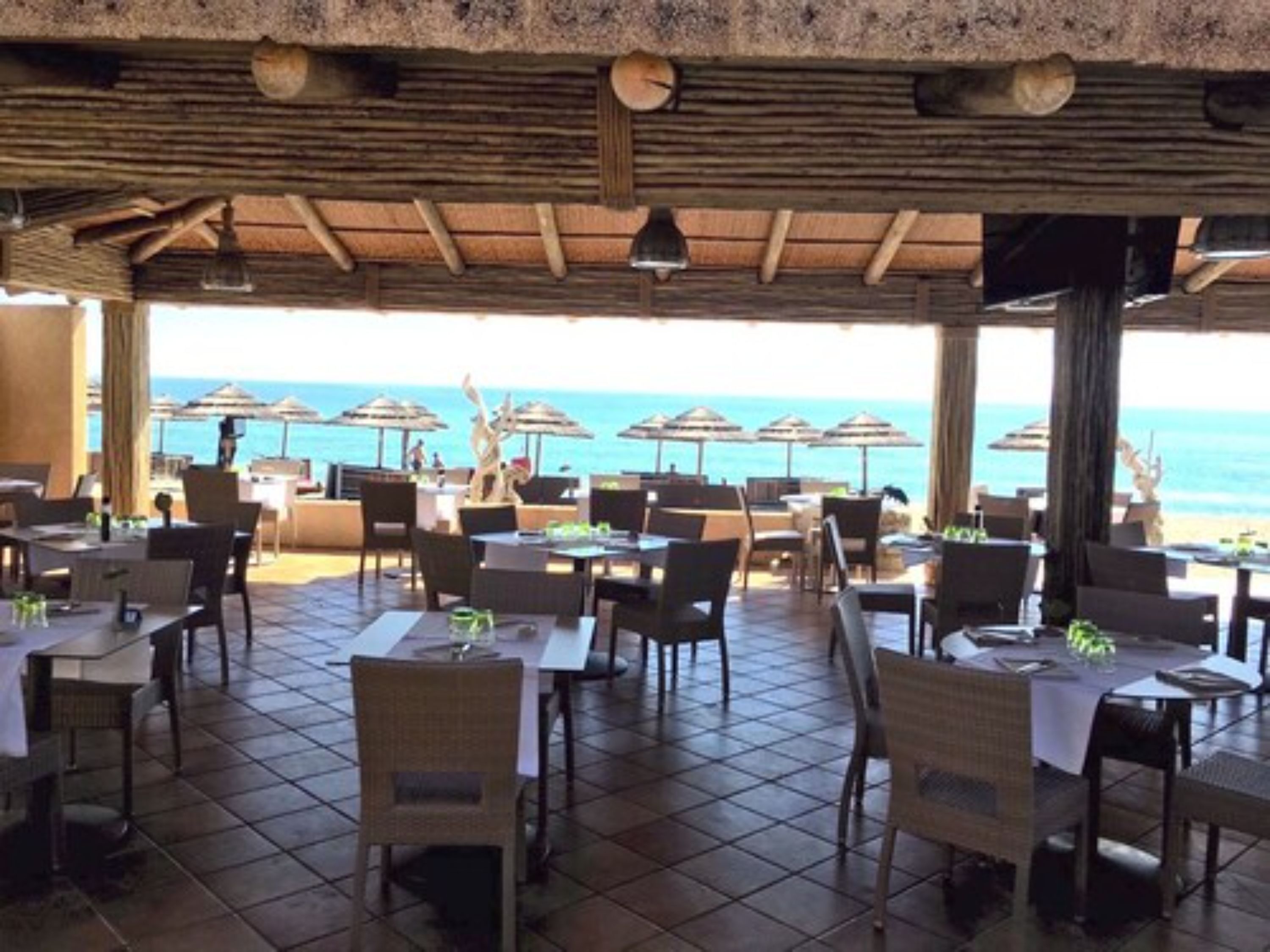 An outdoor dining area with tables and chairs, overlooking the sea.