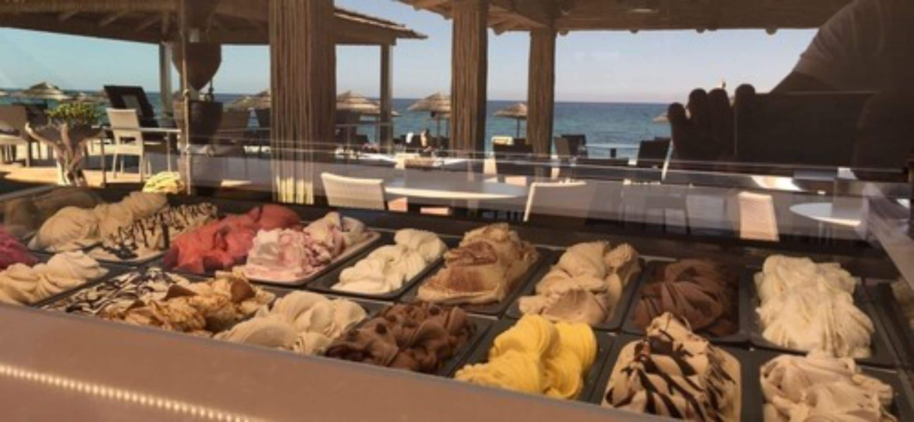 Zona de bufé con diferentes opciones de comida, un entorno junto a la piscina con sombrillas y vistas al mar.