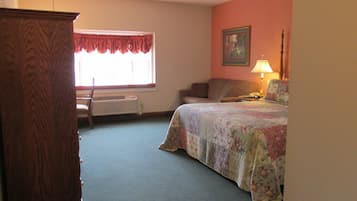 Un dormitorio con cama, cómoda, ventana con cortinas, radiador, lámpara y un cuadro en la pared.
