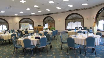 A conference room with multiple tables and chairs, equipped with nameplates and a podium.
