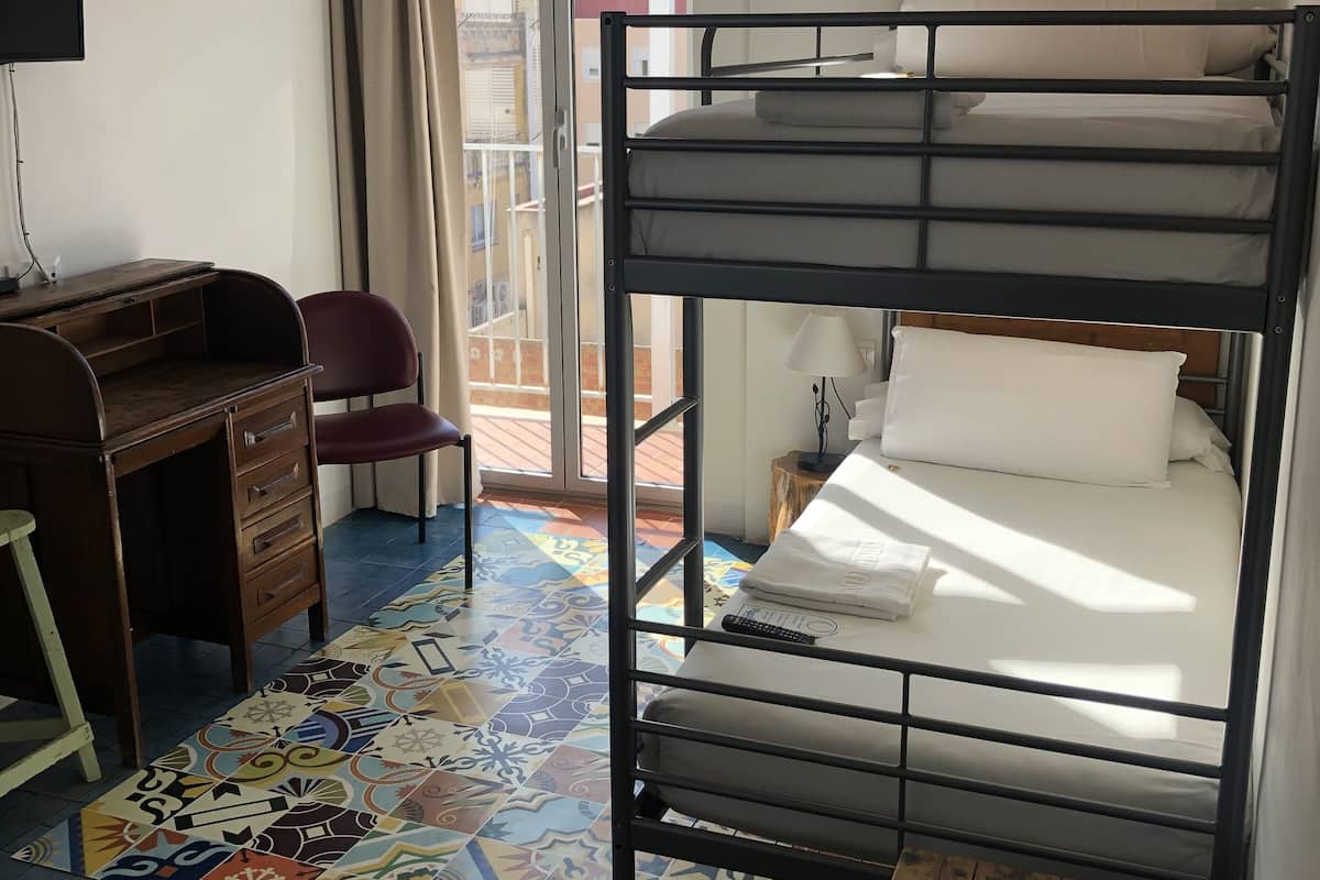 Un dormitorio con literas, un escritorio, una silla y una alfombra colorida.