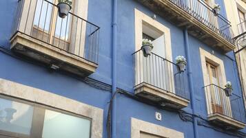 Un edificio de varios pisos con balcones, ventanas amplias y una puerta con el letrero de advertencia de riesgo eléctrico.