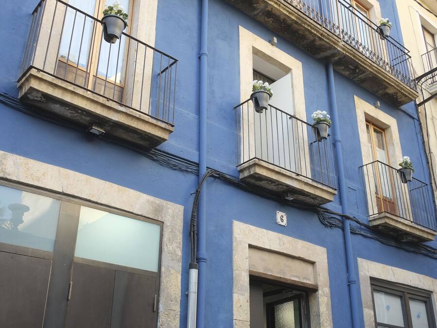Un edificio de varios pisos con balcones, ventanas amplias y una puerta con el letrero de advertencia de riesgo eléctrico.