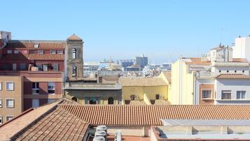 A rooftop terrace with terracotta tiles, a bell tower, and a view of the cityscape.