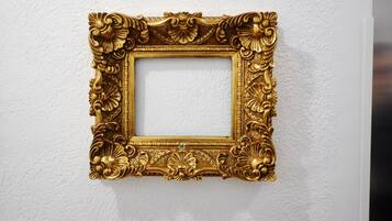 A gold-framed picture hanging on a textured white wall.